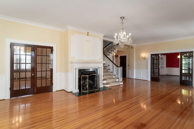 unfurnished living room featuring french doors, crown molding, and wood-type flooring