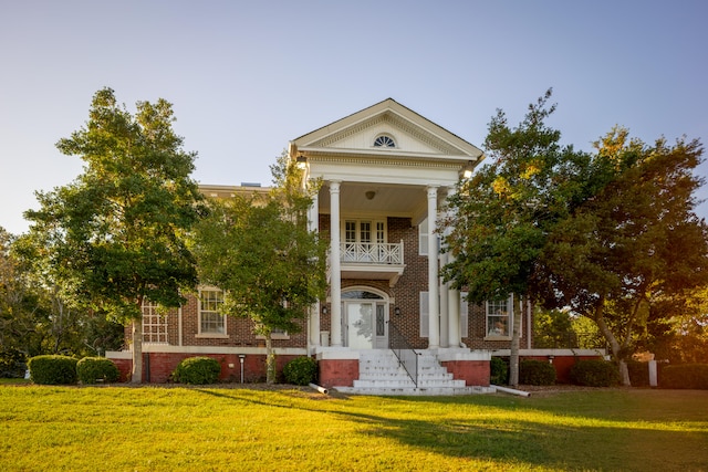 greek revival house with a front yard and a balcony