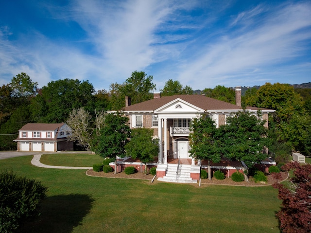 greek revival inspired property featuring a front yard and a garage