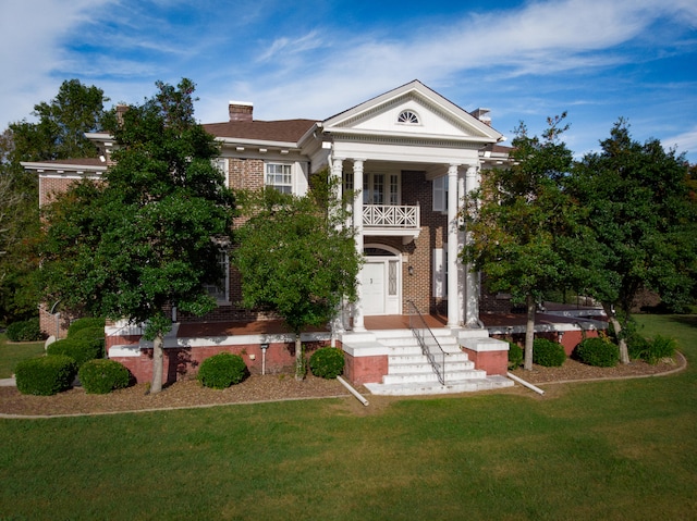 greek revival inspired property featuring a front yard and a balcony