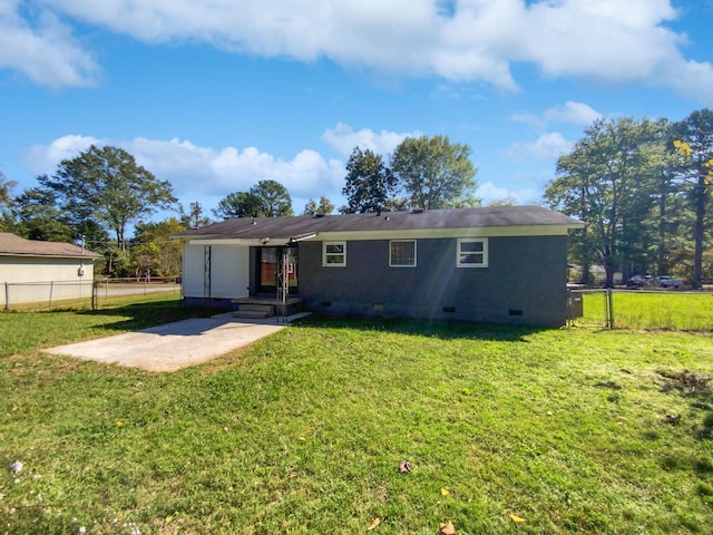 back of house featuring fence, crawl space, and a yard