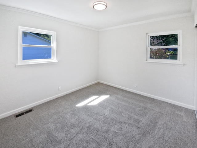 carpeted empty room with baseboards, visible vents, and crown molding