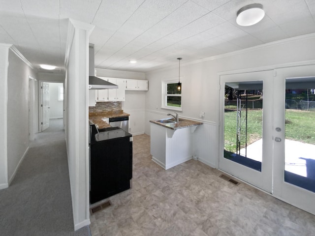 kitchen with kitchen peninsula, white cabinetry, wall chimney exhaust hood, pendant lighting, and decorative backsplash