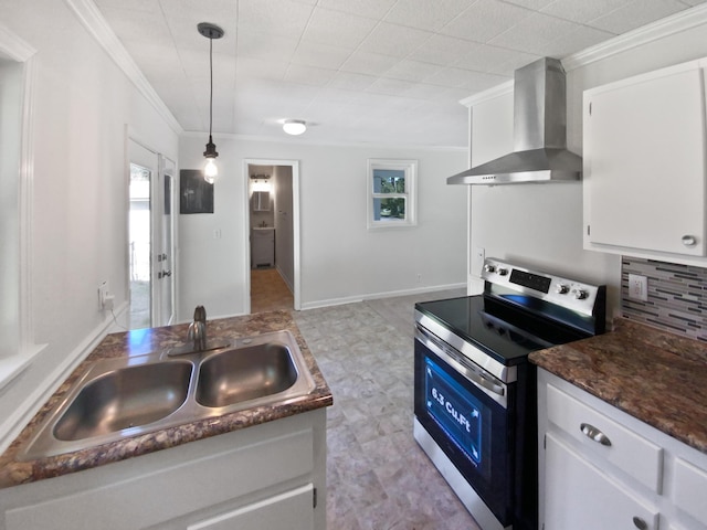 kitchen featuring a sink, stainless steel electric range, white cabinets, wall chimney exhaust hood, and ornamental molding