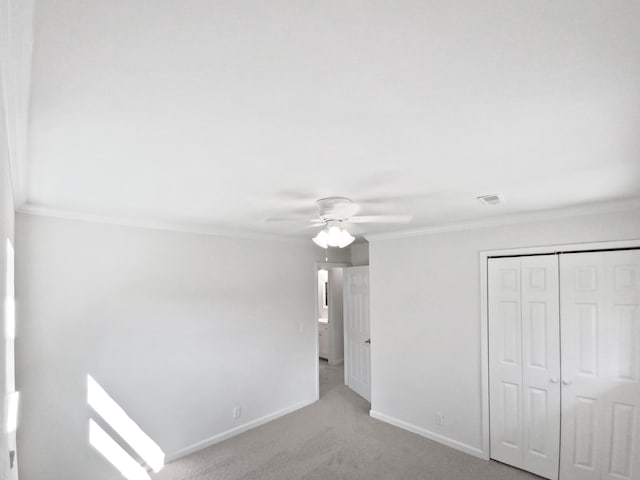 unfurnished bedroom featuring ornamental molding, light colored carpet, a closet, and ceiling fan