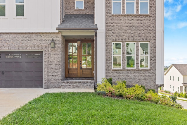 entrance to property with a garage, french doors, and a lawn