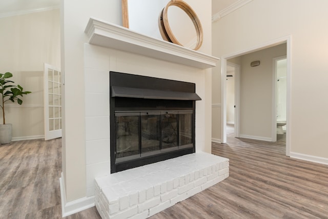 room details with crown molding, wood-type flooring, and a brick fireplace