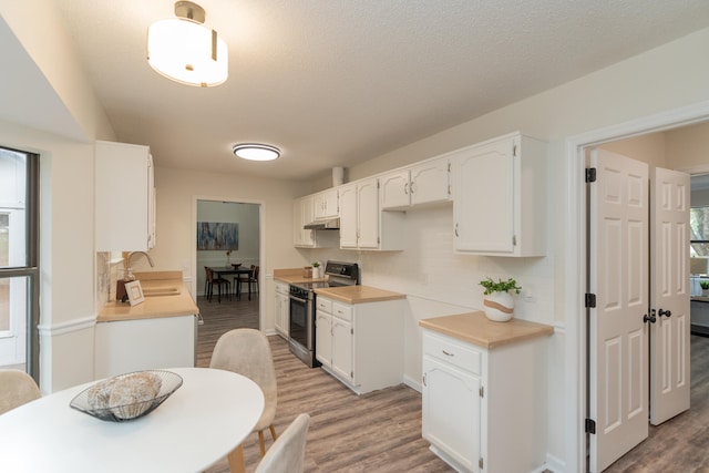 kitchen featuring a wealth of natural light, white cabinets, stainless steel electric stove, and light wood-type flooring