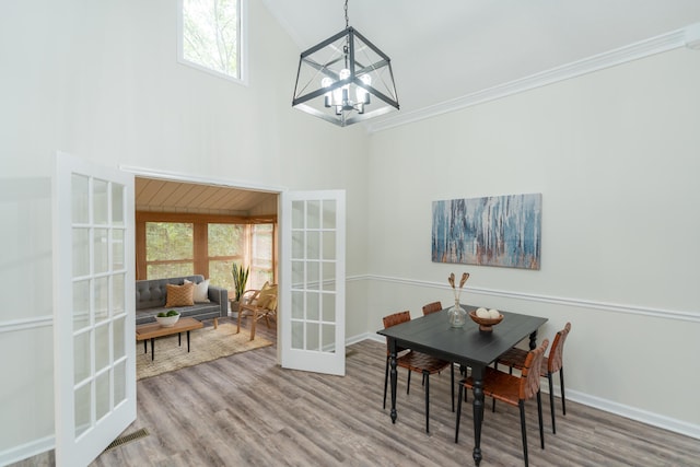 dining area featuring hardwood / wood-style floors, ornamental molding, french doors, and a notable chandelier