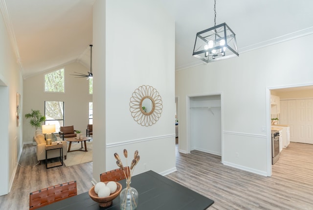 dining area with crown molding, high vaulted ceiling, light hardwood / wood-style flooring, and ceiling fan with notable chandelier