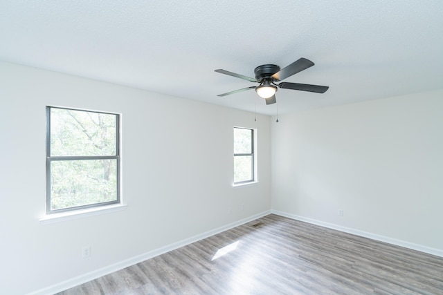 spare room featuring wood-type flooring, a healthy amount of sunlight, and ceiling fan