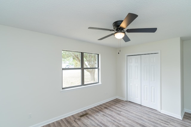 unfurnished bedroom featuring a closet, ceiling fan, a textured ceiling, and light hardwood / wood-style flooring