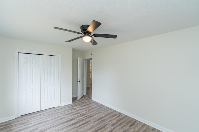 unfurnished bedroom with a closet, ceiling fan, a textured ceiling, and light hardwood / wood-style flooring