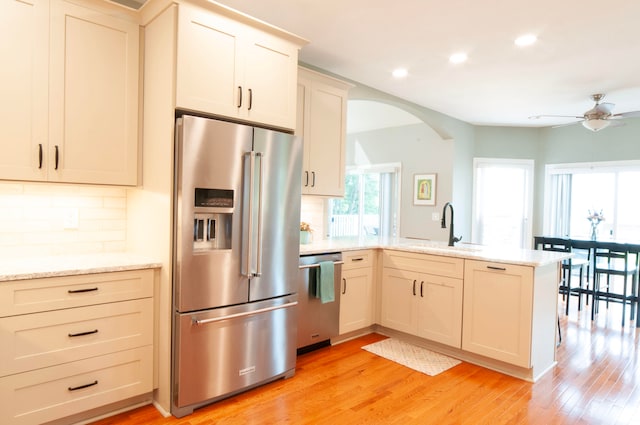 kitchen with sink, kitchen peninsula, stainless steel appliances, and light hardwood / wood-style floors