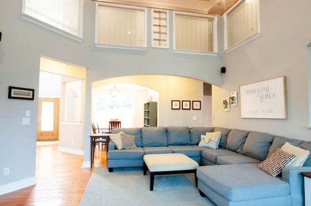 living room with a towering ceiling and light wood-type flooring