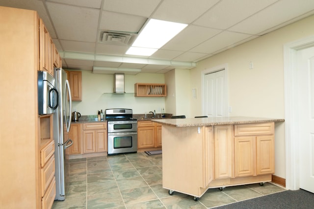 kitchen with wall chimney exhaust hood, a drop ceiling, kitchen peninsula, and stainless steel appliances