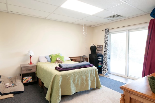 bedroom with access to outside, a drop ceiling, and carpet floors