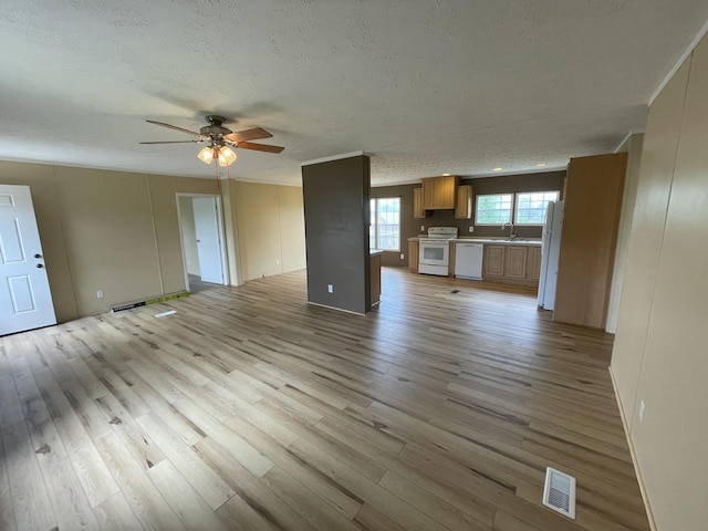 unfurnished living room with light hardwood / wood-style floors, a textured ceiling, sink, and ceiling fan