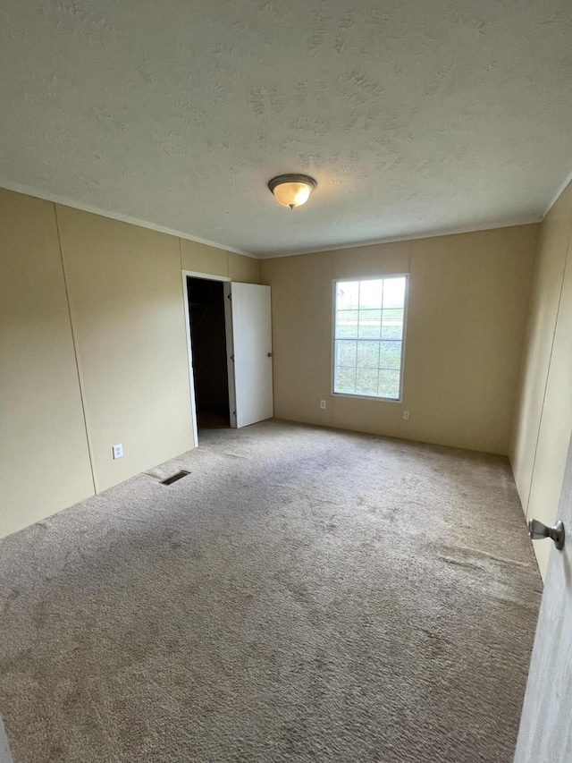 spare room featuring a textured ceiling and light colored carpet