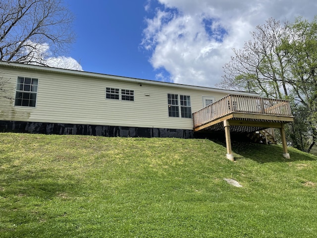 back of property featuring a deck and a lawn