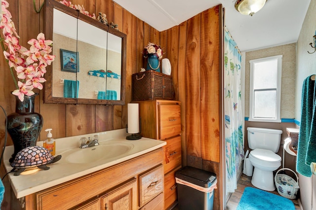 bathroom featuring vanity, wooden walls, and toilet