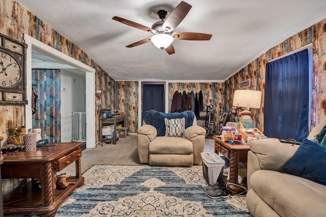 living room with a textured ceiling, carpet flooring, wooden walls, and ceiling fan