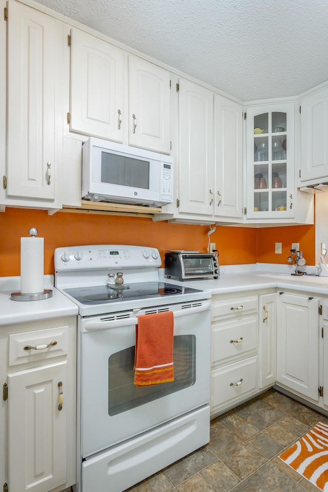 kitchen with white cabinets, a textured ceiling, and white appliances