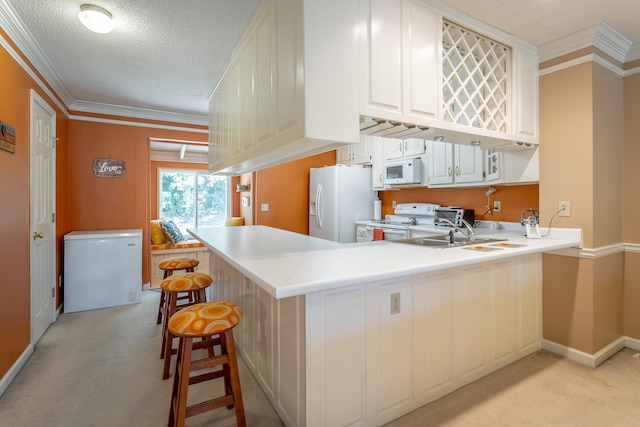 kitchen featuring kitchen peninsula, a kitchen breakfast bar, ornamental molding, light colored carpet, and white appliances