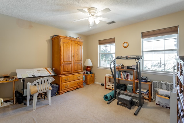 exercise area featuring light carpet, a textured ceiling, and ceiling fan