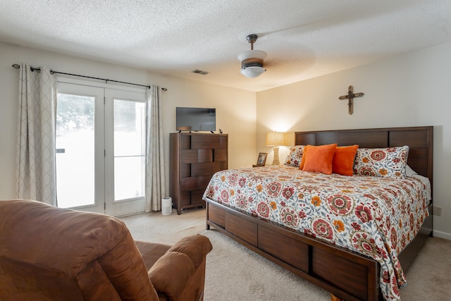 bedroom featuring a textured ceiling, light colored carpet, french doors, and ceiling fan