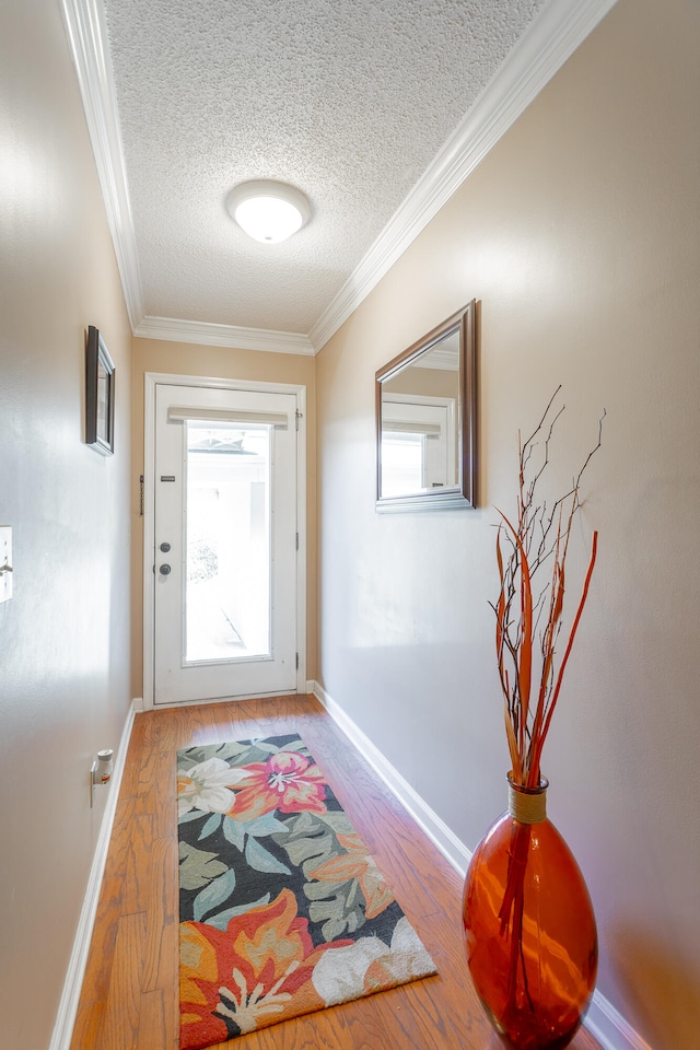 doorway to outside with ornamental molding, hardwood / wood-style floors, a textured ceiling, and a wealth of natural light