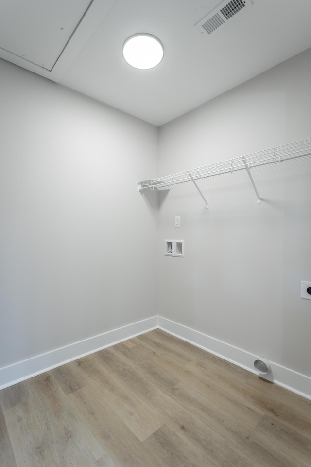 clothes washing area with hookup for a washing machine, light wood-style flooring, laundry area, visible vents, and baseboards