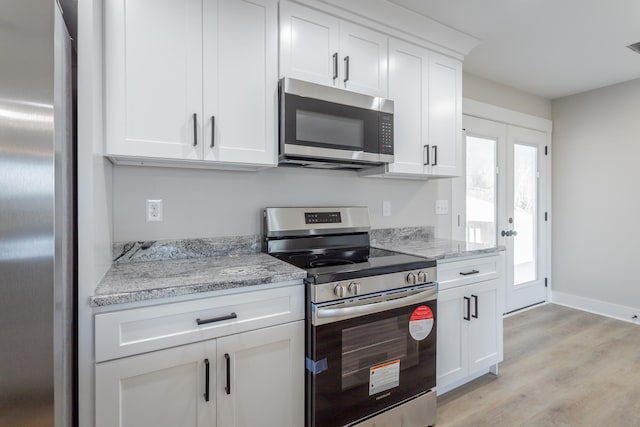 kitchen with stainless steel appliances, light wood-type flooring, white cabinets, and light stone counters