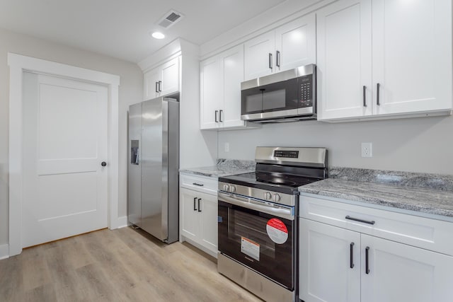 kitchen with visible vents, appliances with stainless steel finishes, light wood-style floors, white cabinets, and light stone countertops