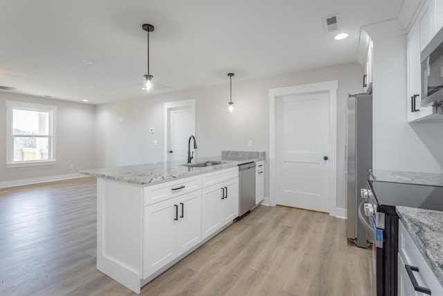 kitchen featuring stainless steel appliances, a sink, light stone countertops, and white cabinets