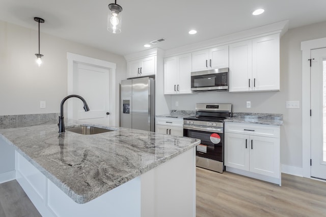 kitchen with appliances with stainless steel finishes, white cabinets, hanging light fixtures, and a peninsula