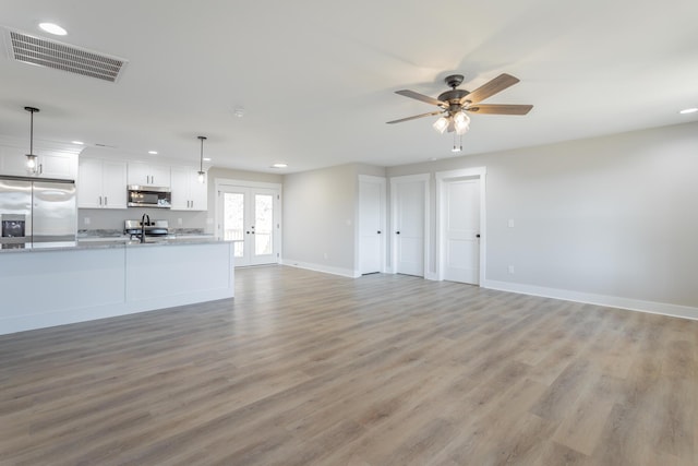 unfurnished living room with french doors, light wood finished floors, recessed lighting, visible vents, and baseboards