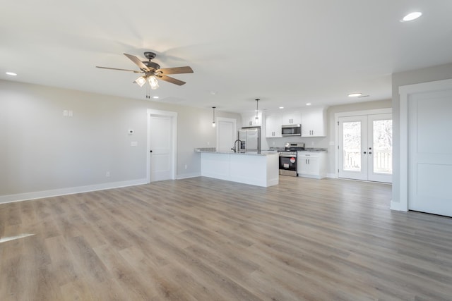 unfurnished living room with baseboards, french doors, recessed lighting, and light wood-style floors