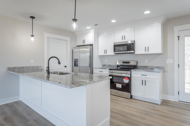 kitchen featuring white cabinetry, pendant lighting, stainless steel appliances, and a sink