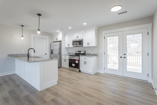 kitchen with stainless steel appliances, white cabinetry, hanging light fixtures, and a sink