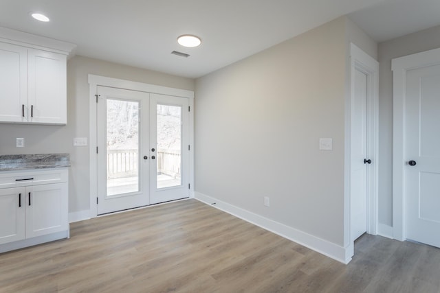 doorway featuring light wood finished floors, baseboards, and french doors