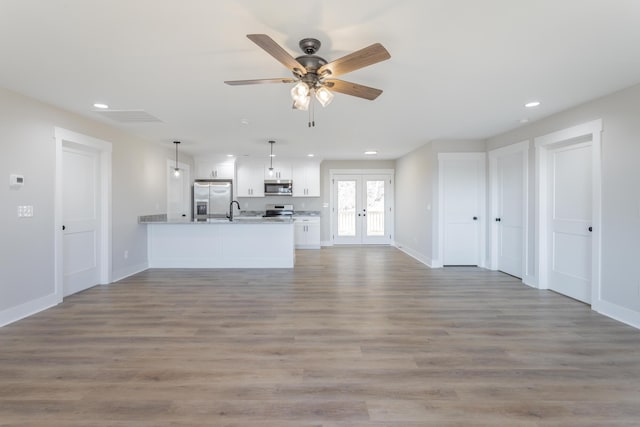 unfurnished living room with baseboards, ceiling fan, wood finished floors, french doors, and recessed lighting