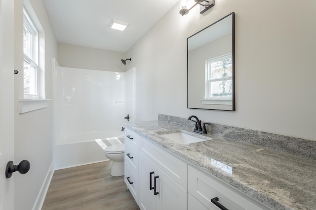 full bath featuring baseboards, toilet, wood finished floors,  shower combination, and vanity