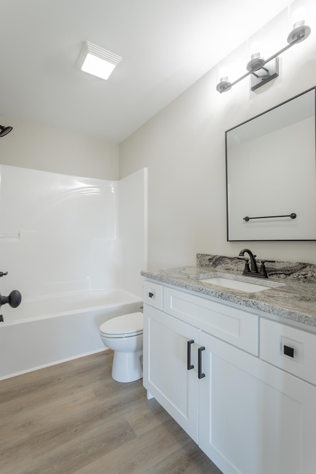 bathroom with shower / bathtub combination, vanity, wood finished floors, and toilet