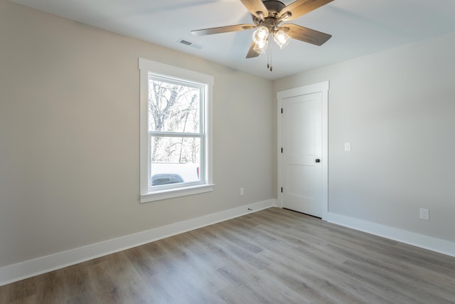 spare room featuring visible vents, ceiling fan, light wood-style flooring, and baseboards