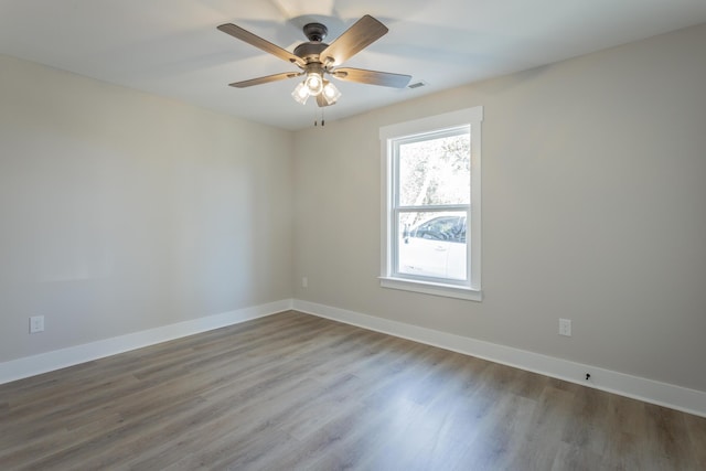 empty room featuring ceiling fan, wood finished floors, visible vents, and baseboards