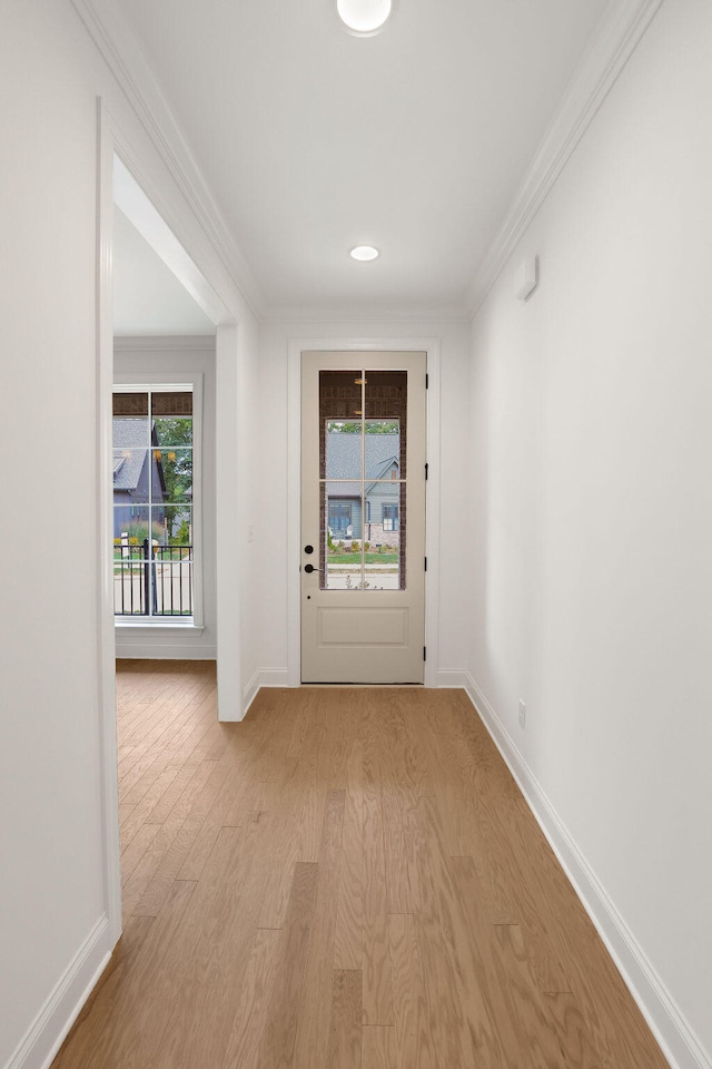 entryway with ornamental molding, a wealth of natural light, and light hardwood / wood-style flooring