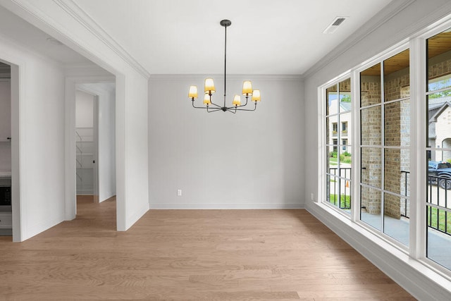 unfurnished dining area featuring an inviting chandelier, ornamental molding, and light hardwood / wood-style flooring