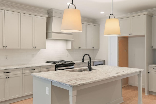 kitchen with backsplash, an island with sink, decorative light fixtures, gas stove, and light stone counters