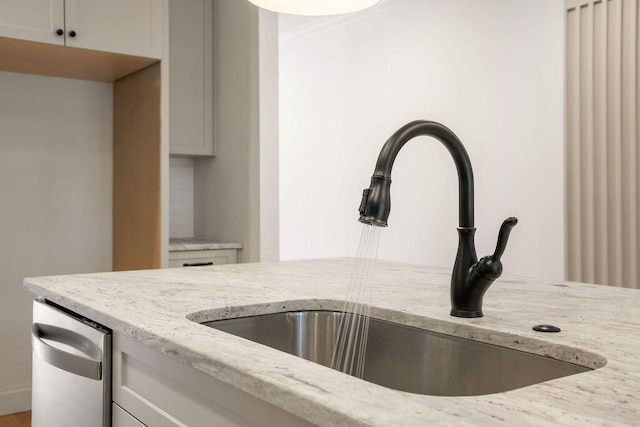 interior details with white cabinetry, light stone counters, and sink